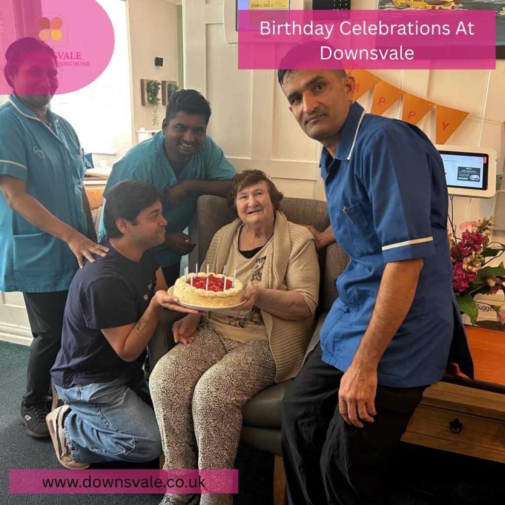 Elderly woman celebrating her birthday with caregivers, holding a cake and smiling.