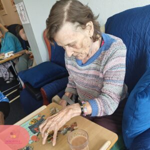 Elderly woman placing pieces together while doing a jigsaw puzzle.