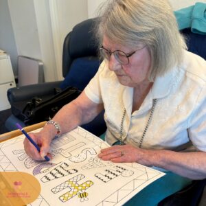 Senior woman focused on colouring a patterned activity page at a care home.