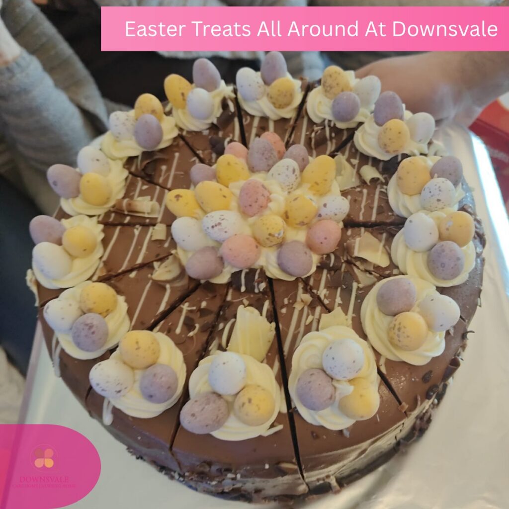 Close-up of a decorated chocolate cake with mini eggs and icing slices.