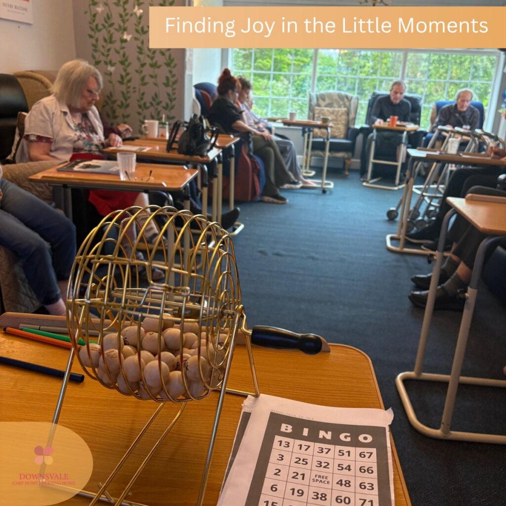 Care home residents gathered for a bingo activity with a bingo cage and cards in the foreground.