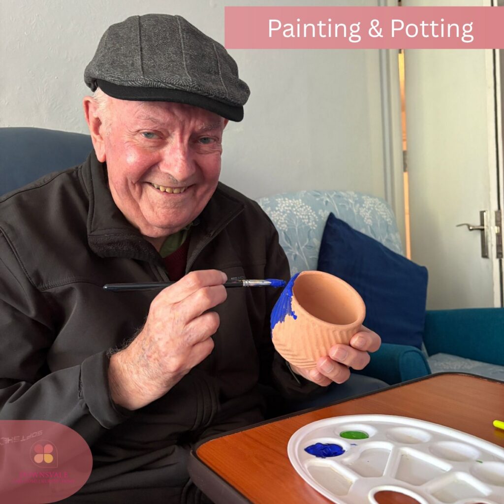 Happy elderly man painting a pot during a craft activity.