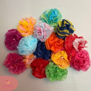 Colorful handmade tissue paper flowers arranged on a wall.