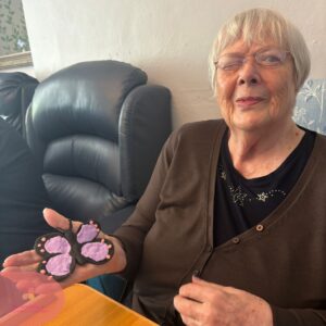 Senior resident proudly showing a purple butterfly artwork.