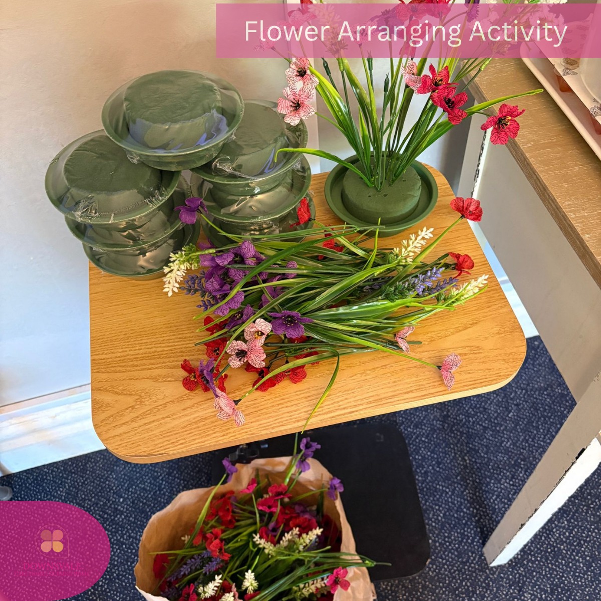 Table with artificial flowers, foam bases, and supplies for a flower arranging activity.