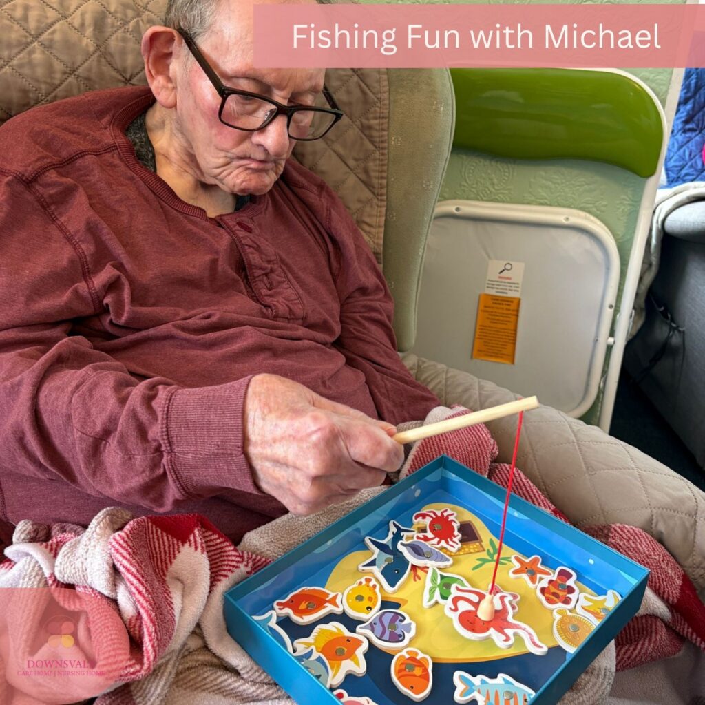 Older man focused on a fishing game activity in a cosy care home setting.