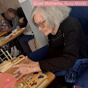 Elderly woman focused on a matching game activity in a comfortable care home setting.