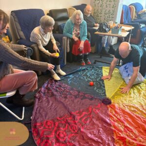 Care home residents taking part in a group ball game activity.