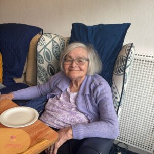 Smiling elderly resident relaxing in a comfortable chair.