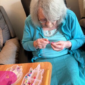 Resident crafting jewelry with colorful beads and string.