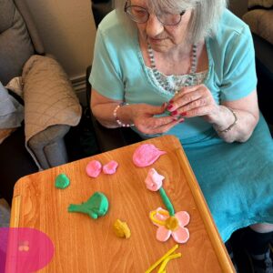Resident displaying a handmade flower made from modeling clay.