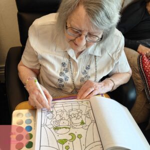 Elderly resident colouring a picture book during a relaxing care home activity.