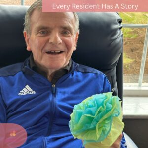 Smiling senior man holding a handmade paper flower.