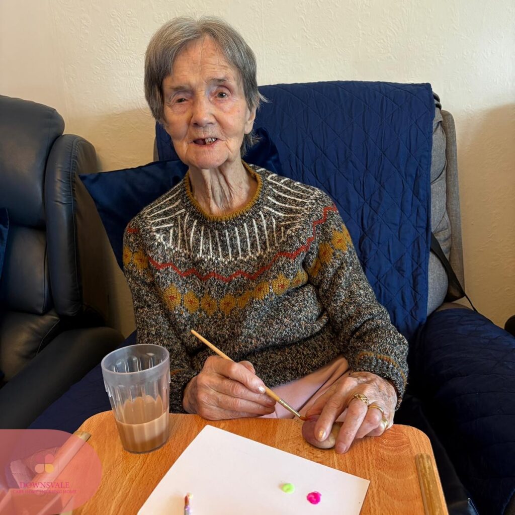 Elderly female resident painting during a creative arts activity at Downsvale Care Home.