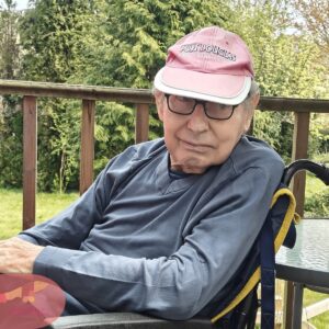 Resident sitting outdoors on a patio, enjoying the fresh air and garden surroundings.