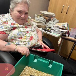 Resident relaxing in a chair and engaging with a small animal activity.