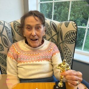 Resident beaming with joy while holding a fun award trophy.