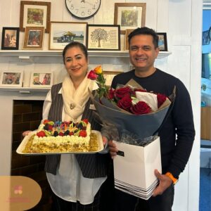 Care home team members celebrating a birthday with cake, flowers, and smiles.