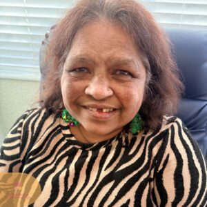 Resident smiling warmly, wearing festive holiday earrings and a patterned top.