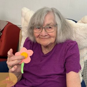Resident smiling while proudly holding a handmade flower craft.
