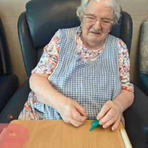 Resident enjoying a modelling clay activity at a care home table.