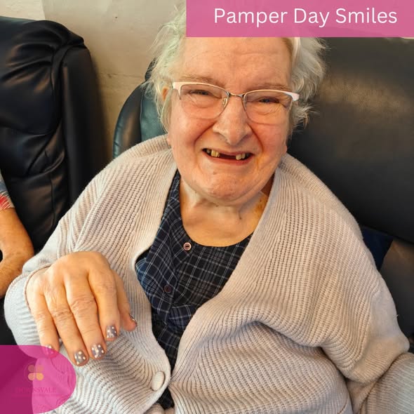 Resident smiling happily and displaying freshly painted nails on pamper day.