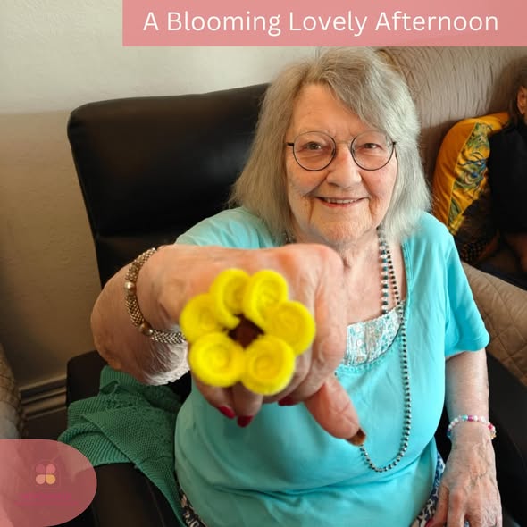 Smiling resident proudly showing a bright yellow flower craft creation.