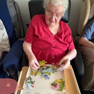 Resident completing a colourful jigsaw puzzle at a table.