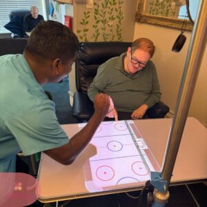 Caregiver and resident play an interactive table game together.