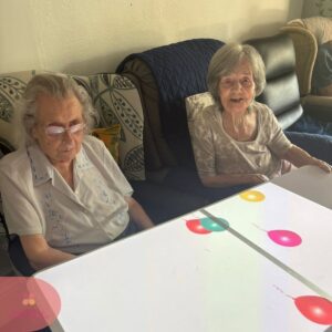 Two residents enjoying interactive balloon projections on a sensory table.