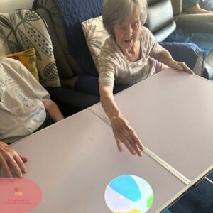 Resident stretching to touch a moving beach ball projection.