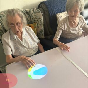 Two residents reaching for a projected beach ball on an interactive table.