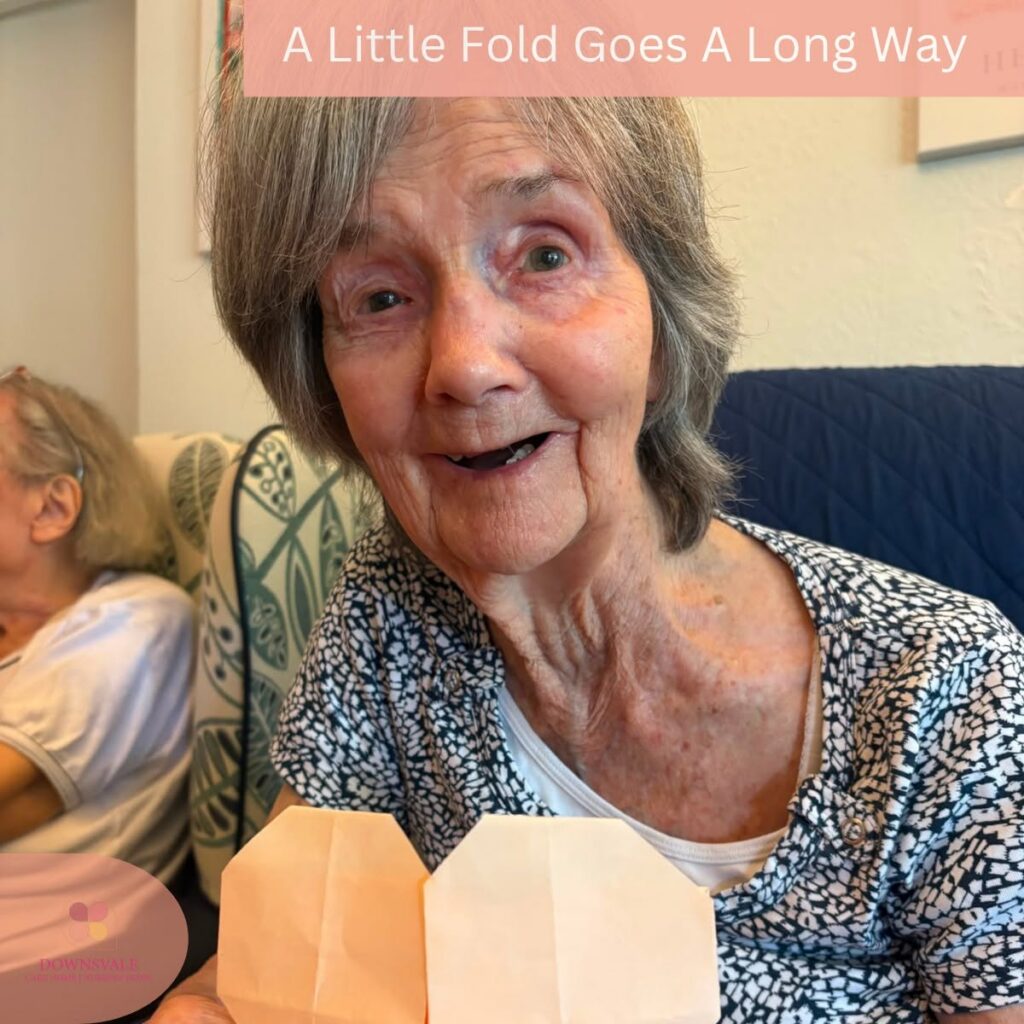 Happy resident proudly showing a handmade paper heart after a fun craft activity.