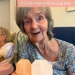 Happy resident proudly showing a handmade paper heart after a fun craft activity.