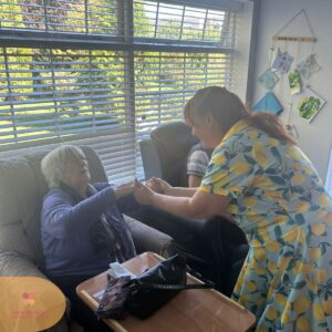 Caregiver warmly holding a resident's hands during a friendly activity.