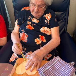 Resident carefully folding paper to create a heart during an arts and crafts activity.