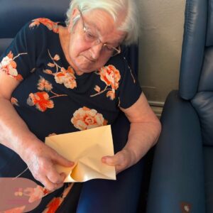 Resident carefully folding paper as part of a relaxing craft session.