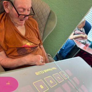 Elderly resident taking part in a memory game on an interactive touch table in a care home.