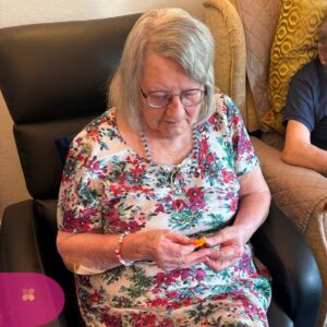 Senior resident concentrating on a creative craft session with pipe cleaners.