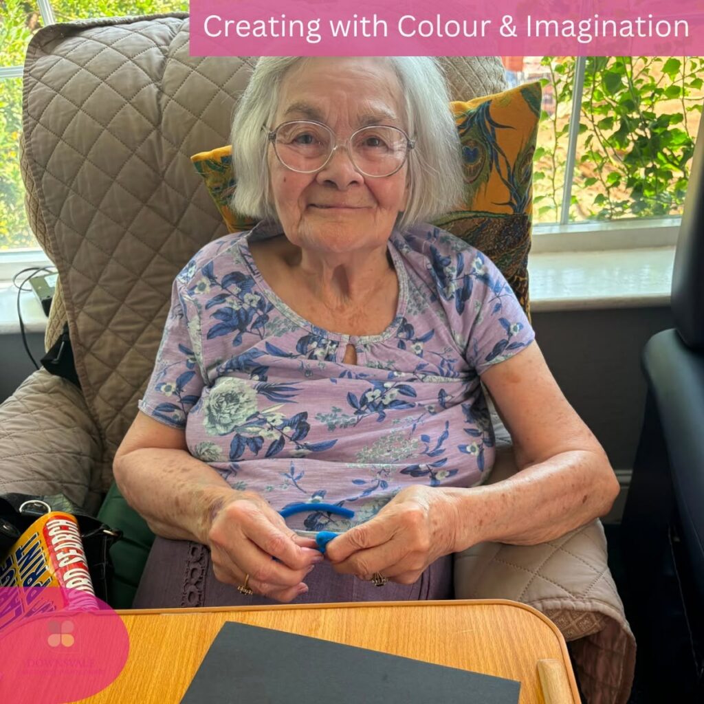 Smiling elderly resident enjoying a creative pipe cleaner activity in the care home.