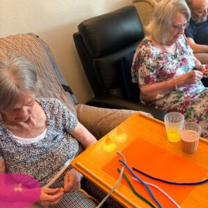 Residents enjoying a colourful pipe cleaner craft activity in a nursing home.