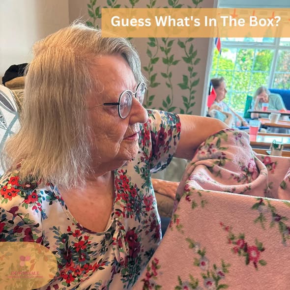 Resident participating in a "Guess What's in the Box?" sensory activity with a floral blanket.