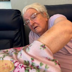 Elderly resident reaching out to explore a soft floral blanket by touch.