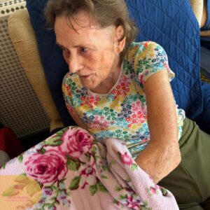 Female resident examining a floral blanket during a sensory engagement activity.