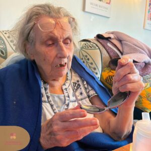 Elderly resident holding a pair of sunglasses while taking part in a sensory activity.