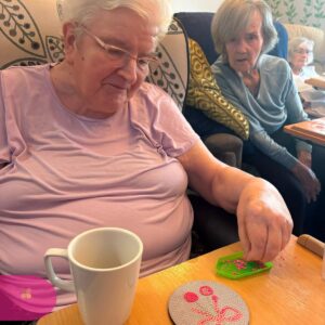 Resident enjoying a relaxing diamond painting activity while selecting pink beads at the table.