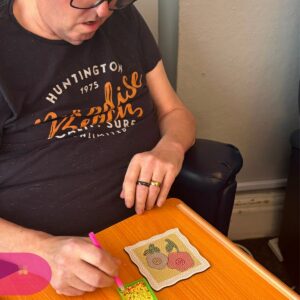 Resident focused on completing a colourful flower diamond painting activity with care and precision.