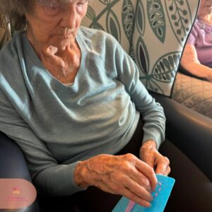 Resident carefully stitching a colourful felt design during a creative activity.