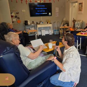 Residents taking part in a fun karaoke session with music and classic song lyrics on screen.