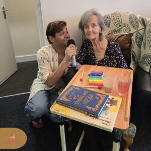 Resident smiling during a one-to-one sing-along session with a visiting performer.